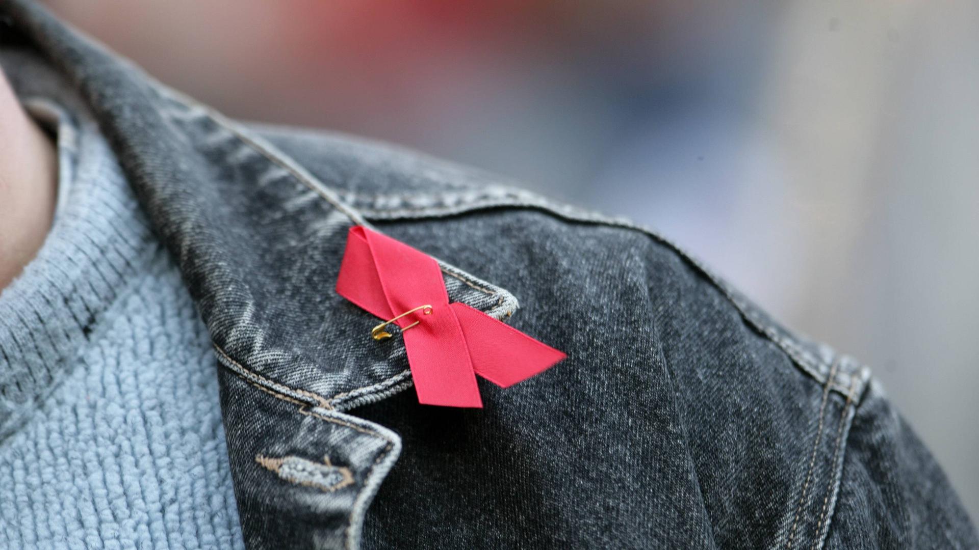 Rote Aidsschleife auf schwarzer Jeansjacke