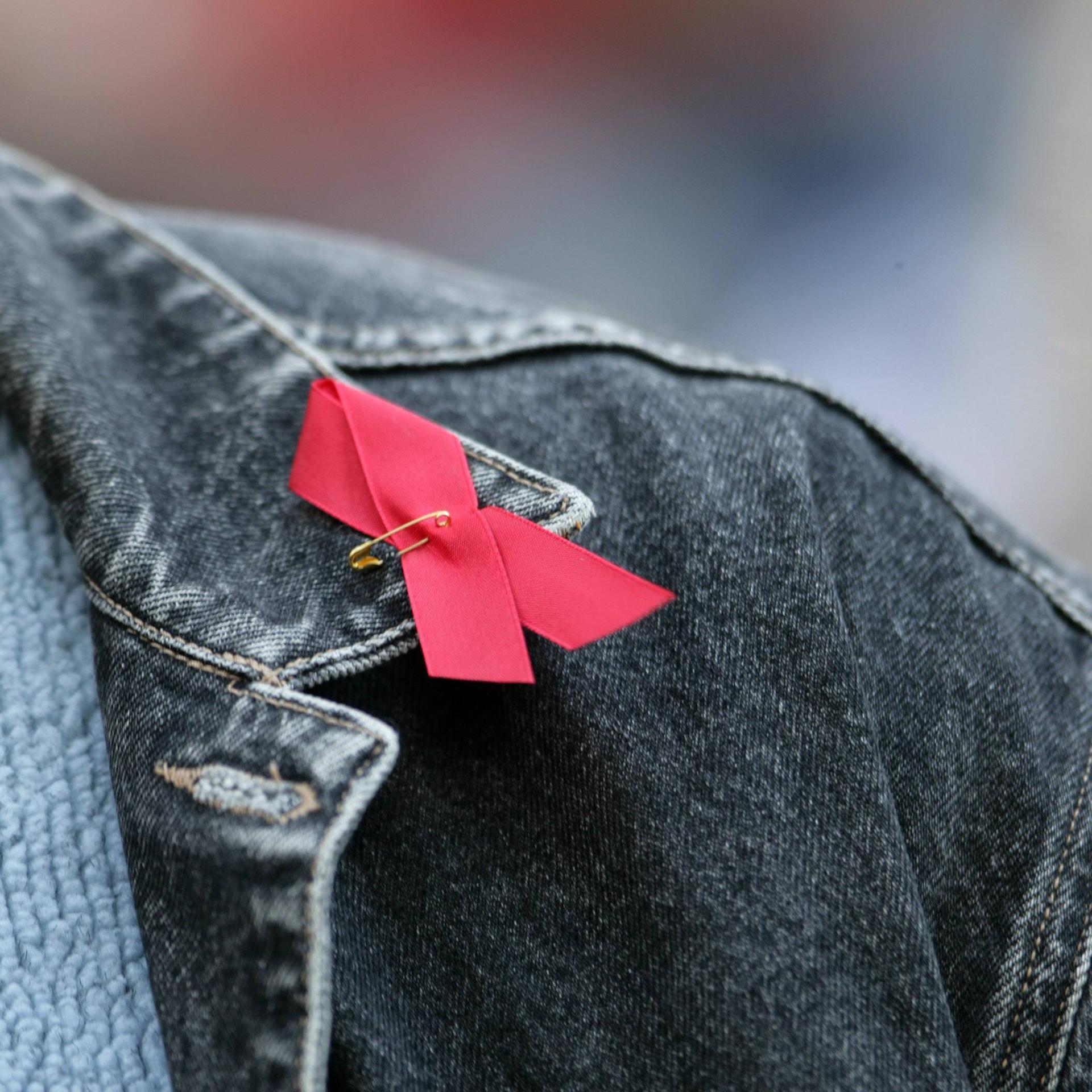 Rote Aidsschleife auf schwarzer Jeansjacke