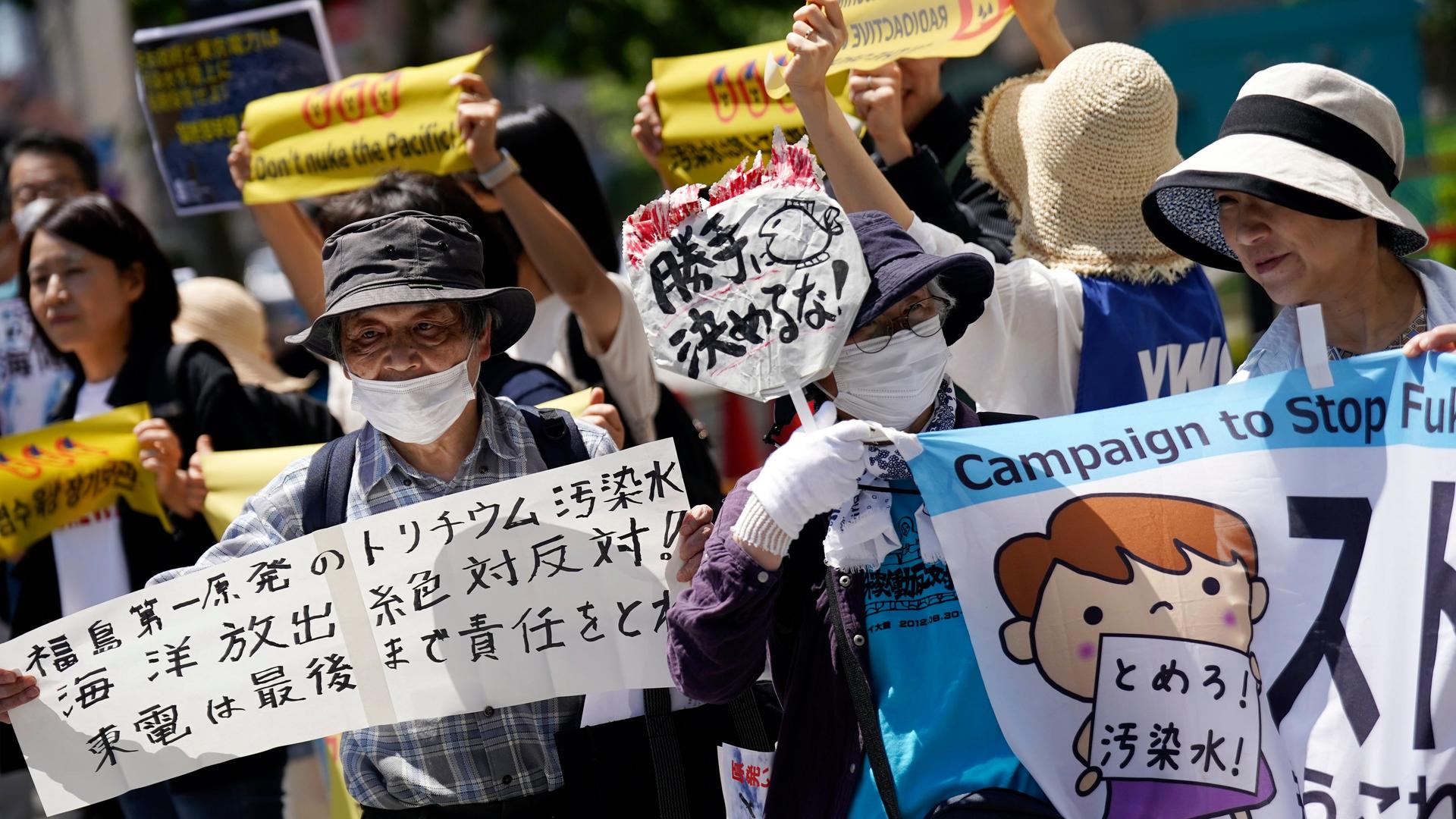 Aktivisten protestieren gegen das Ablassen von verstrahltem Wasser aus Fukushima in den Pazifik, sie halten Plakate vor sich und in die Höhe.