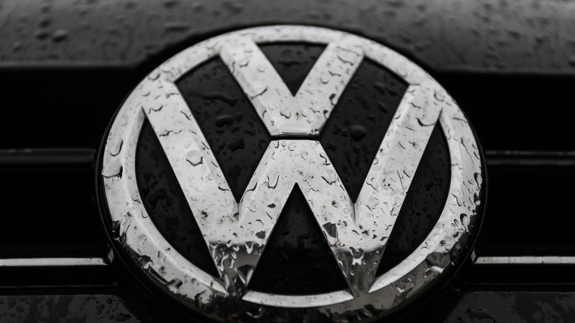 Das VW-Logo auf einem Auto ist von Regentropfen überzogen.
