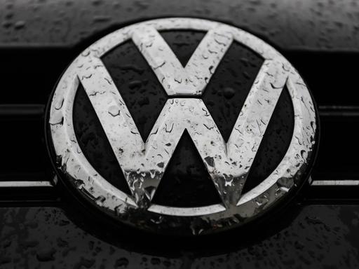 Das VW-Logo auf einem Auto ist von Regentropfen überzogen.