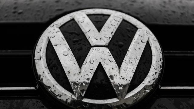 Das VW-Logo auf einem Auto ist von Regentropfen überzogen.