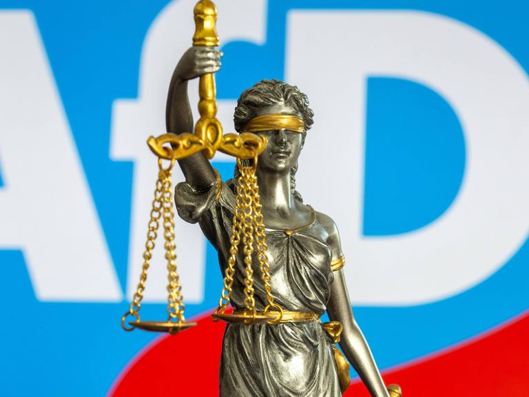 Die Bronzestatue der Justitia vor dem Logo der AfD – Symbolbild für den Rechtsstreit um die Einstufung der Partei als "gesichert rechtsextremistisch".