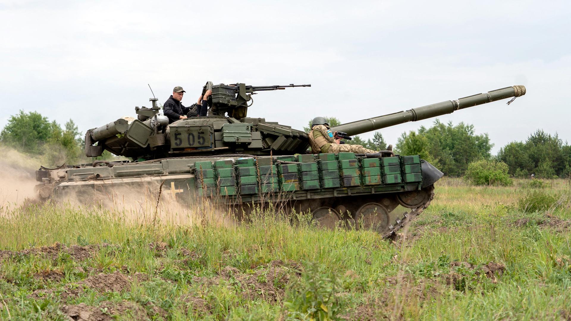 Ein Panzer in der Ukraine fährt durch eine Wiese.