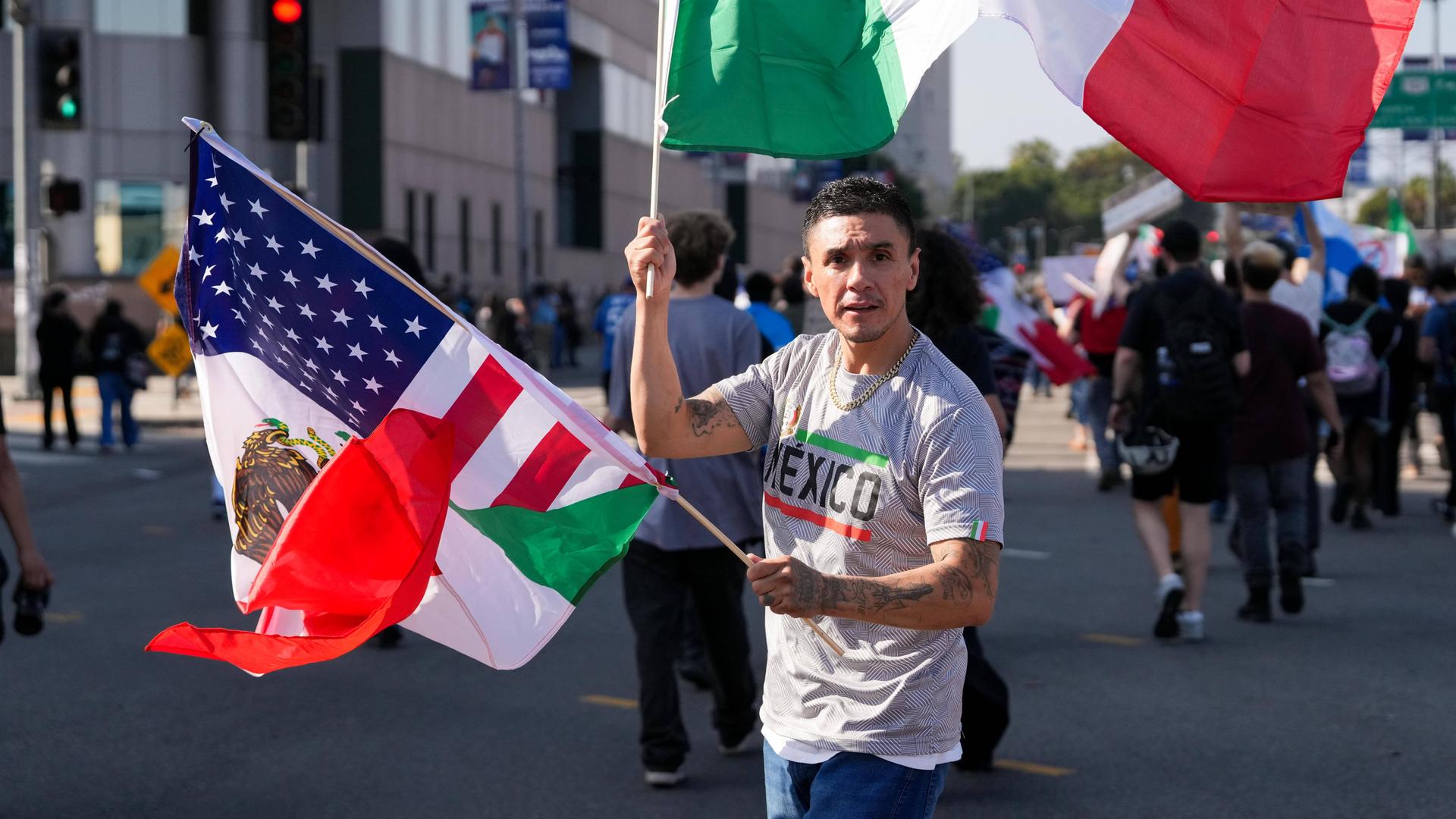 Ein Latino mit mexikanischer und US-Flagge auf einer Straße in Los Angeles