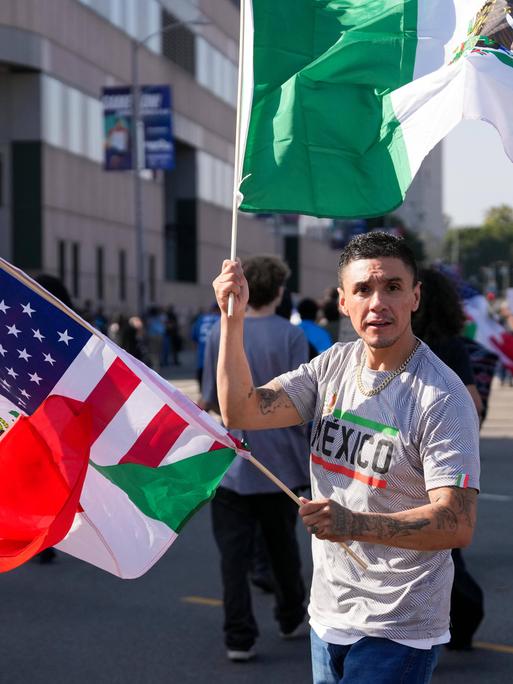 Ein Latino mit mexikanischer und US-Flagge auf einer Straße in Los Angeles
