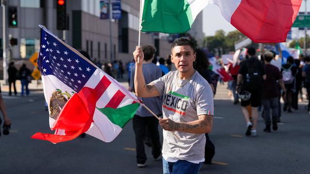 Ein Latino mit mexikanischer und US-Flagge auf einer Straße in Los Angeles