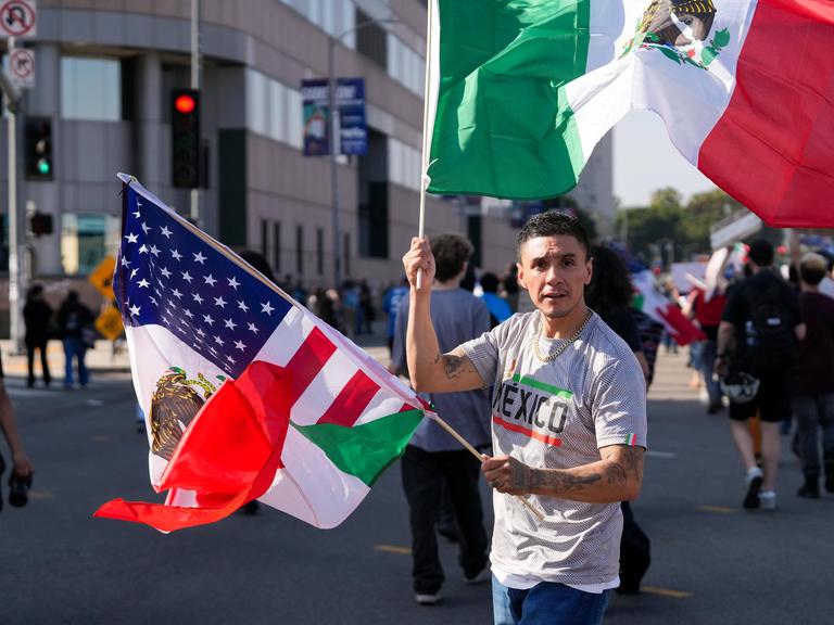 Ein Latino mit mexikanischer und US-Flagge auf einer Straße in Los Angeles