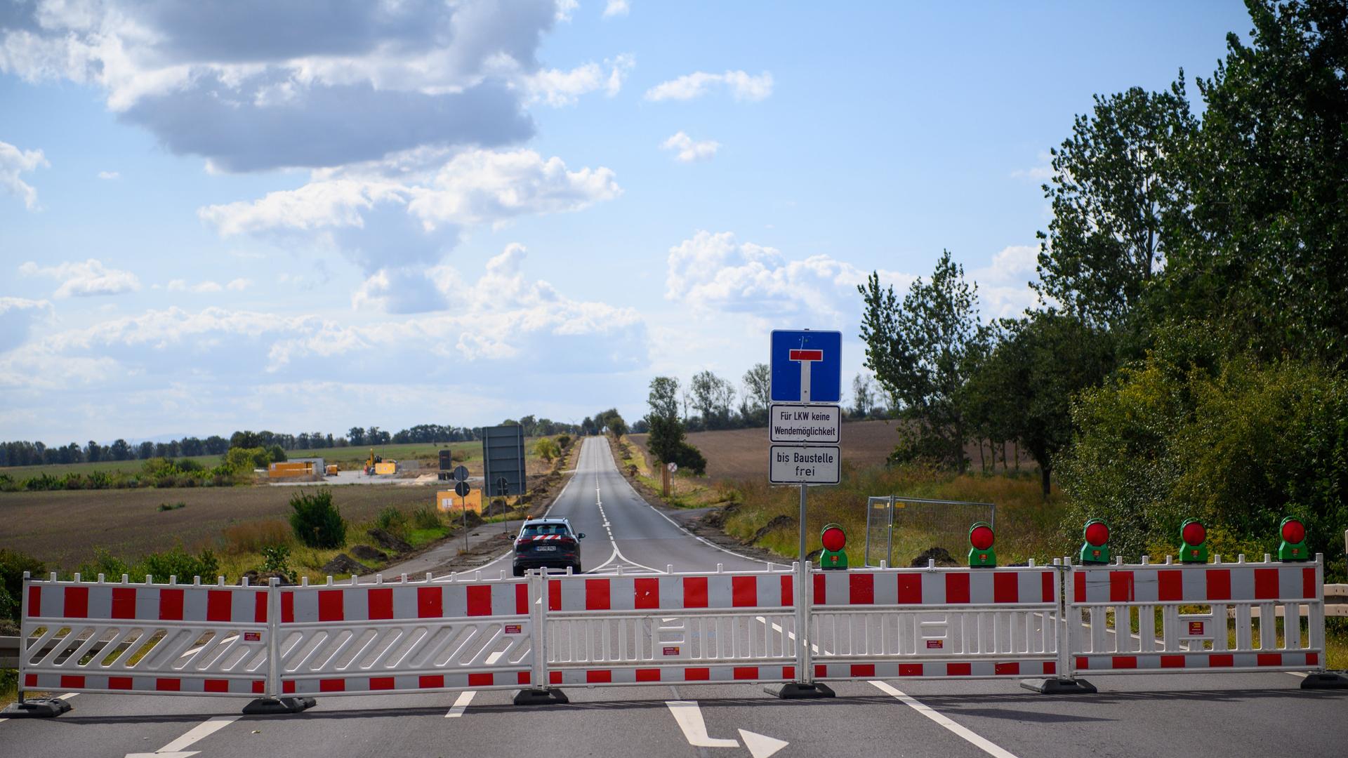 Ein Baustellenfahrzeug fährt über eine gesperrte Straße zu einer Zufahrt zum Baugelände der Intel-Chipfabrik auf dem Eulenberg nahe Magdeburg. (21.08.2024)