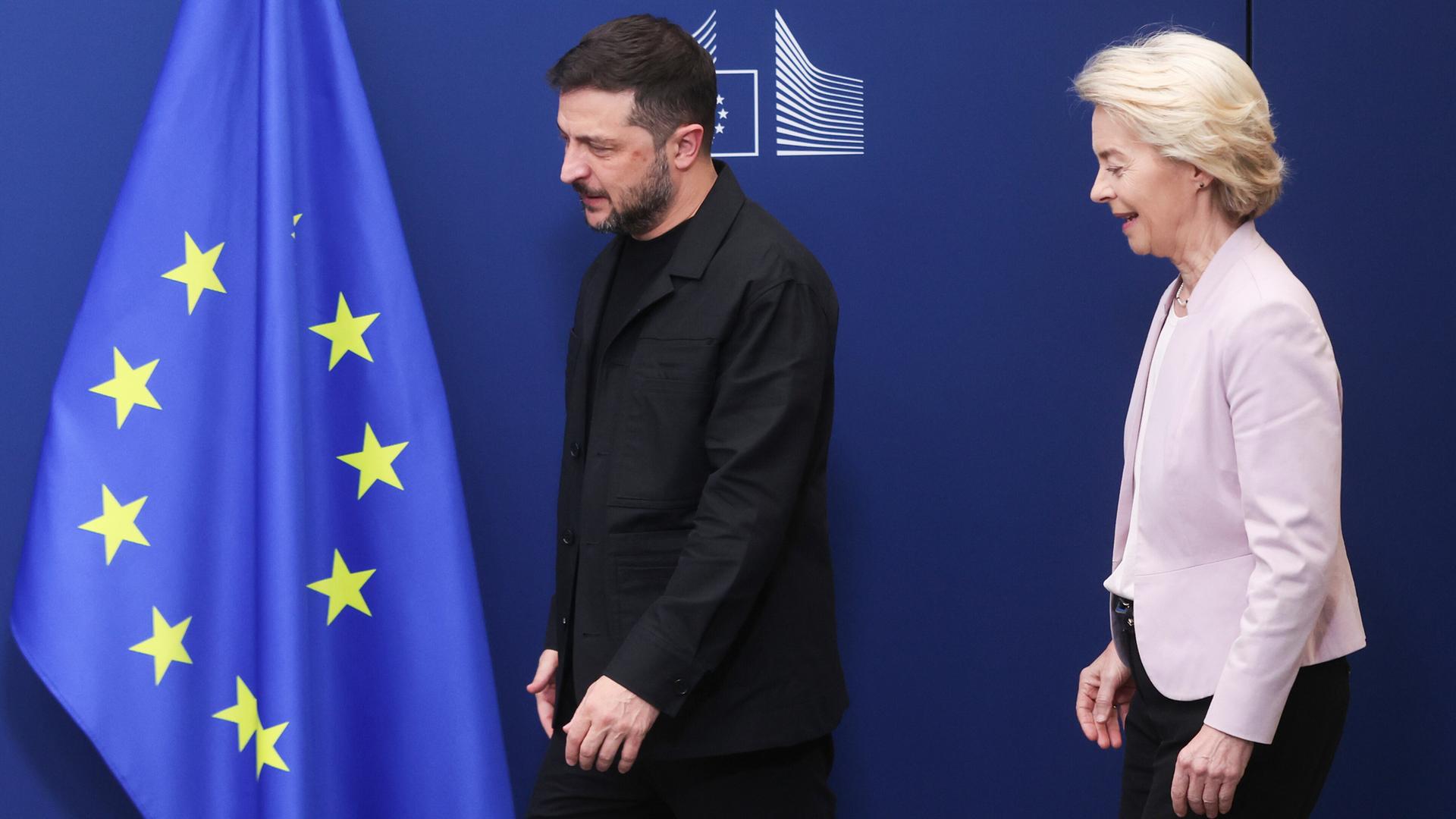 Der ukrainische Präsident Selenskyj und EU-Kommissionspräsidentin von der Leyen stehen vor einem blauen Hintergrund mit einer europäischen Flagge. Der ukrainische Präsident Selenskyj und EU-Kommissionspräsidentin von der Leyen stehen vor einem blauen Hintergrund mit einer europäischen Flagge.