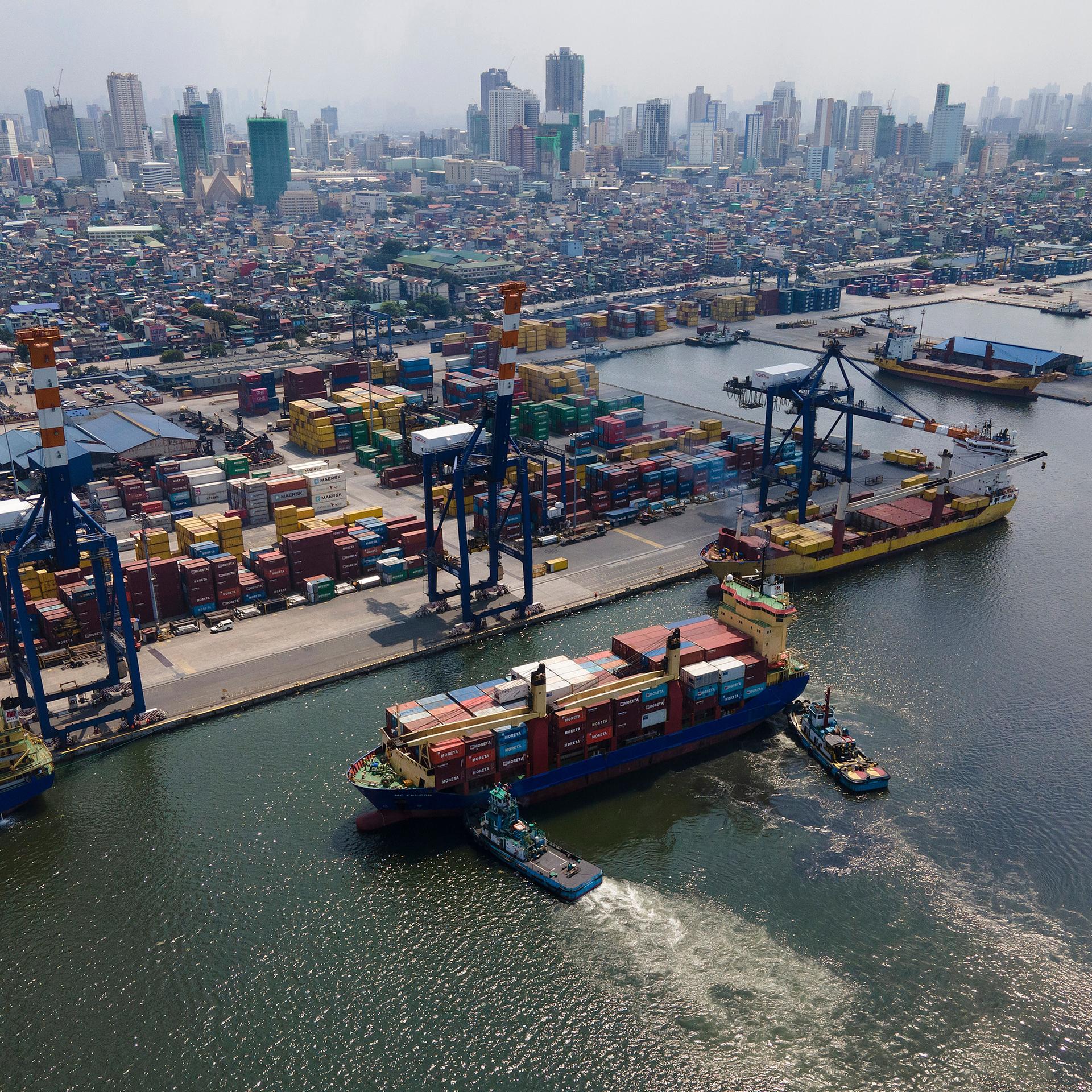 Ein voll beladenes Containerschiff wird in den Hafen von Manila gezogen.