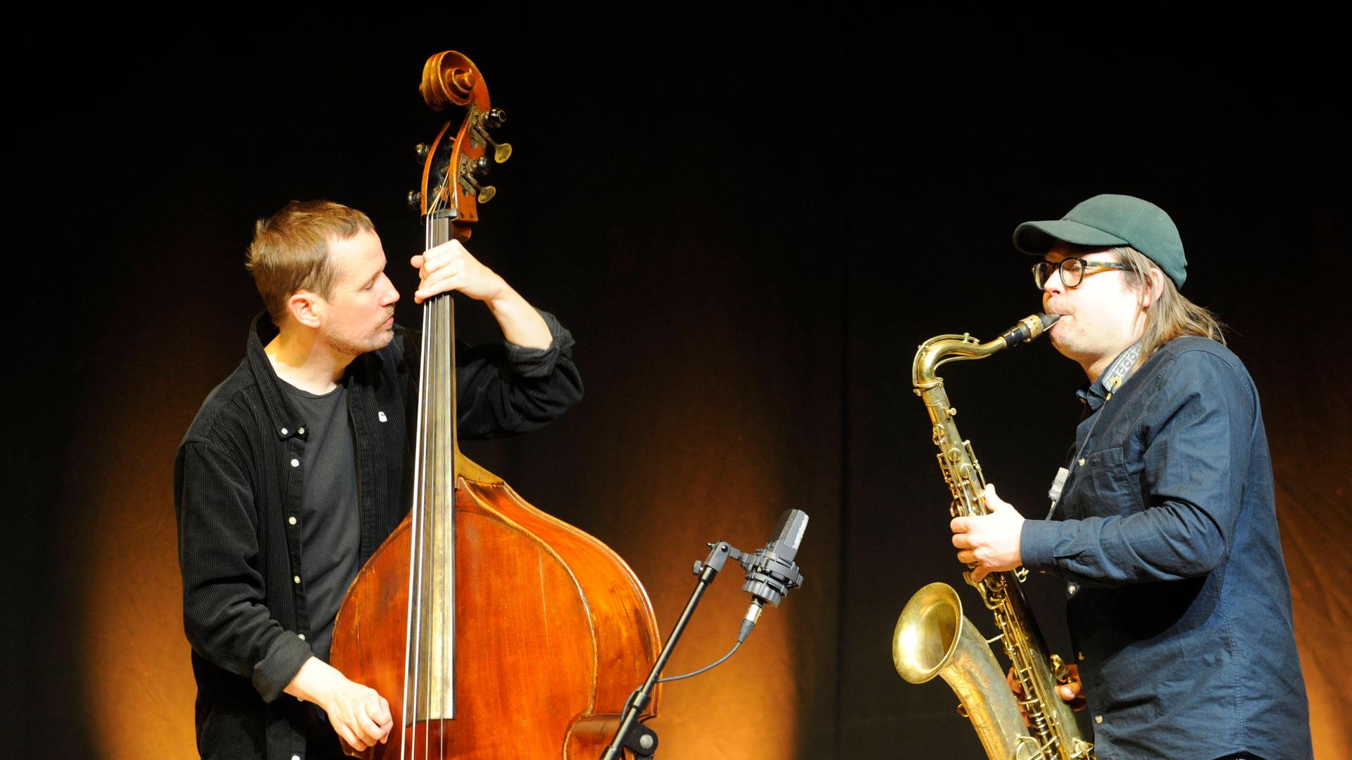 Der Bassist Petter Eldh und der Saxofonist Otis Sandsjö stehen sich mit ihren Instrumenten sspielend gegenüber.