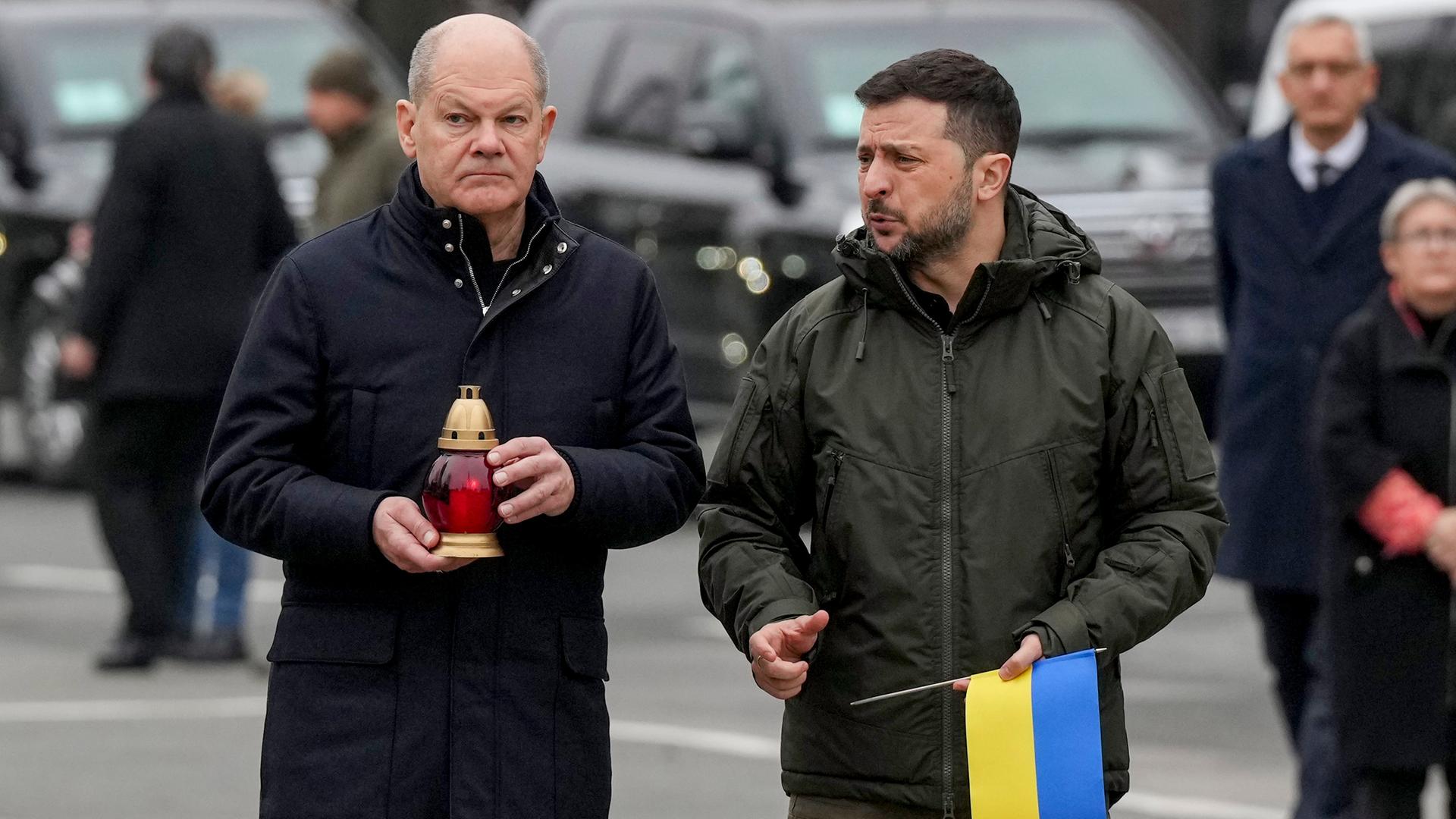 Bundes-Kanzler Scholz und der Präsident von dem Land Ukraine, Selenskyj, gehen zu einem Mahnmal für gefallene Soldaten.