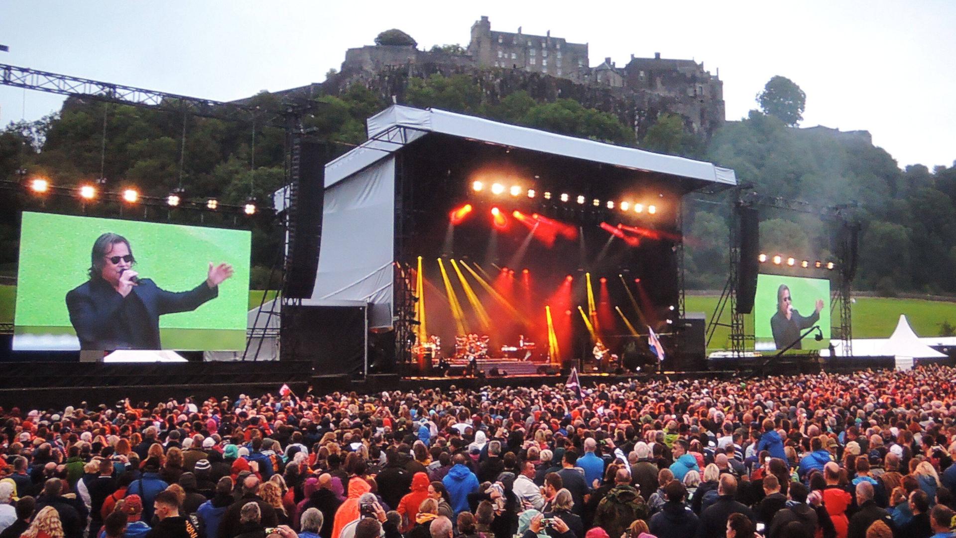 Die schottische Band Runrig bei ihrem letzten Auftritt 2018 von dem Stirling Castle. Sänger Bruce Guthro ist auf einer Leinwand groß zu sehen.