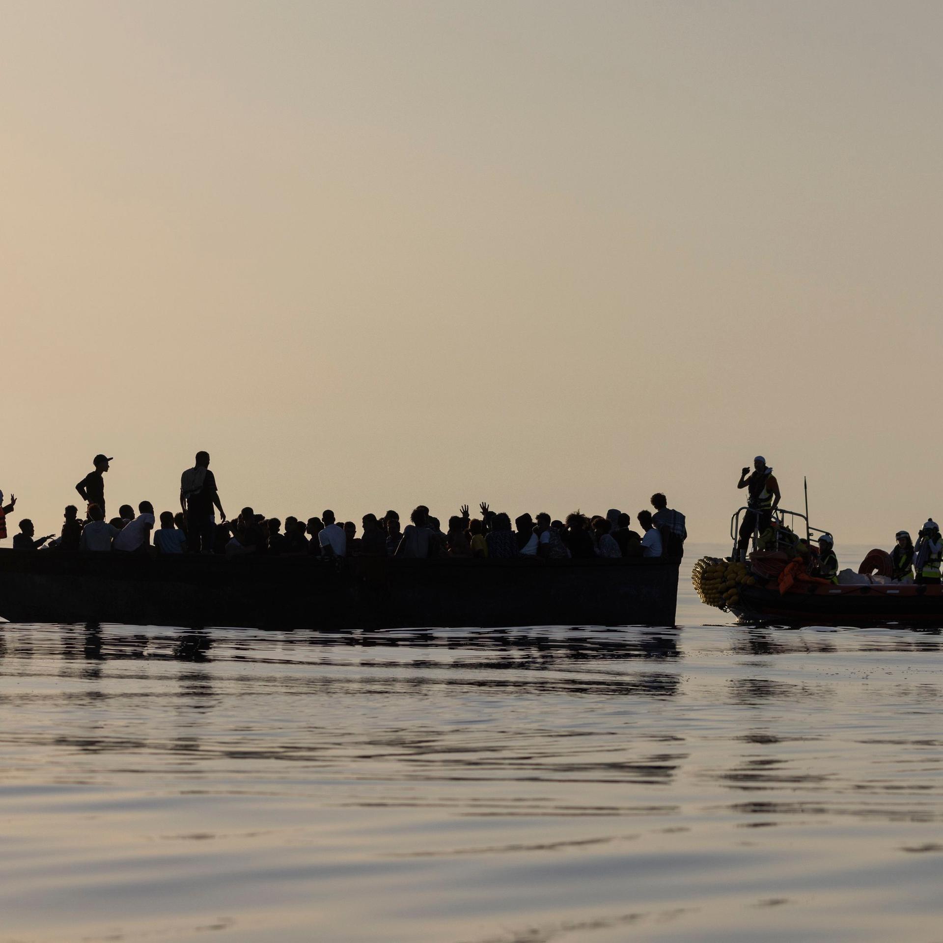 Migranten in einem Boot werden von Besatzungsmitgliedern der Ocean Viking gerettet.