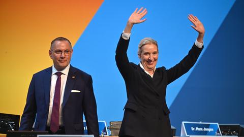 Weidel und Chrupalla stehen nebeneinander auf der Parteitagsbühne. Weidel winkt mit beiden Händen.