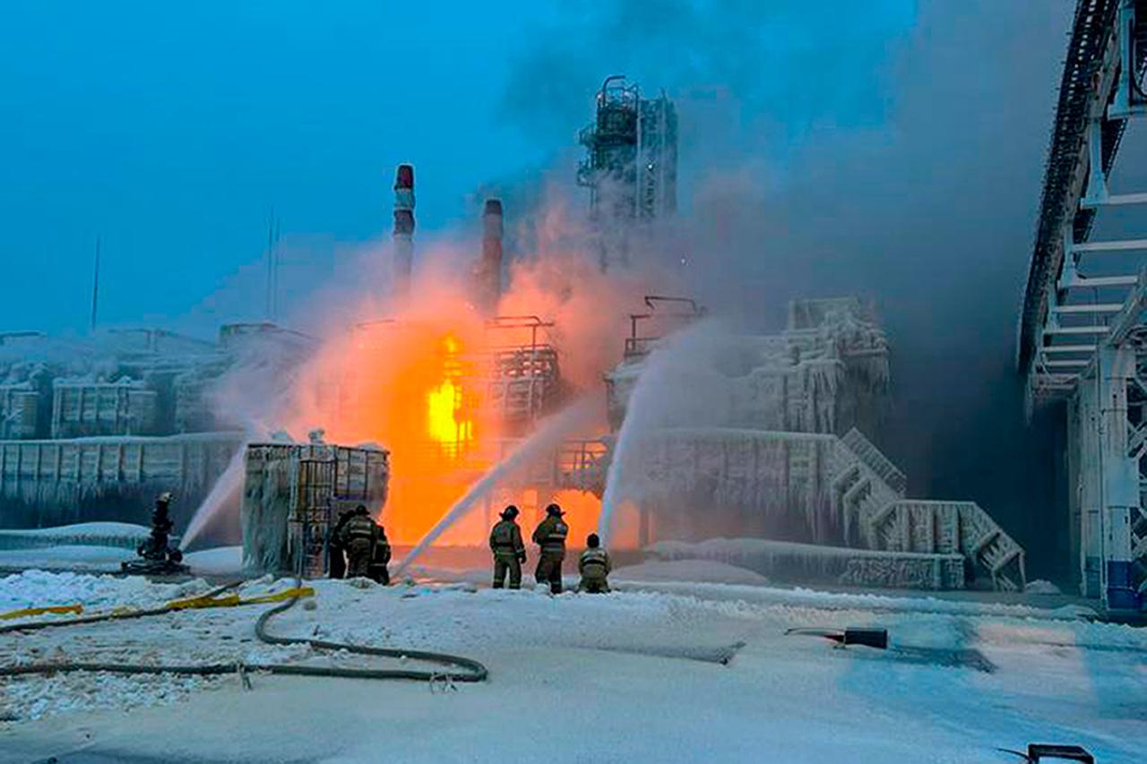 Feuerwehrleute stehen in Eis und Schnee vor eiem brennenden Erdgas-Terminal.