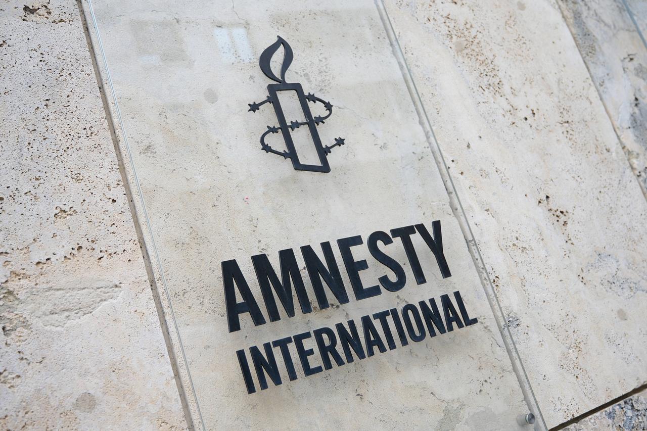 Der Schriftzug und das Logo von Amnesty International auf einer Steinwand. 