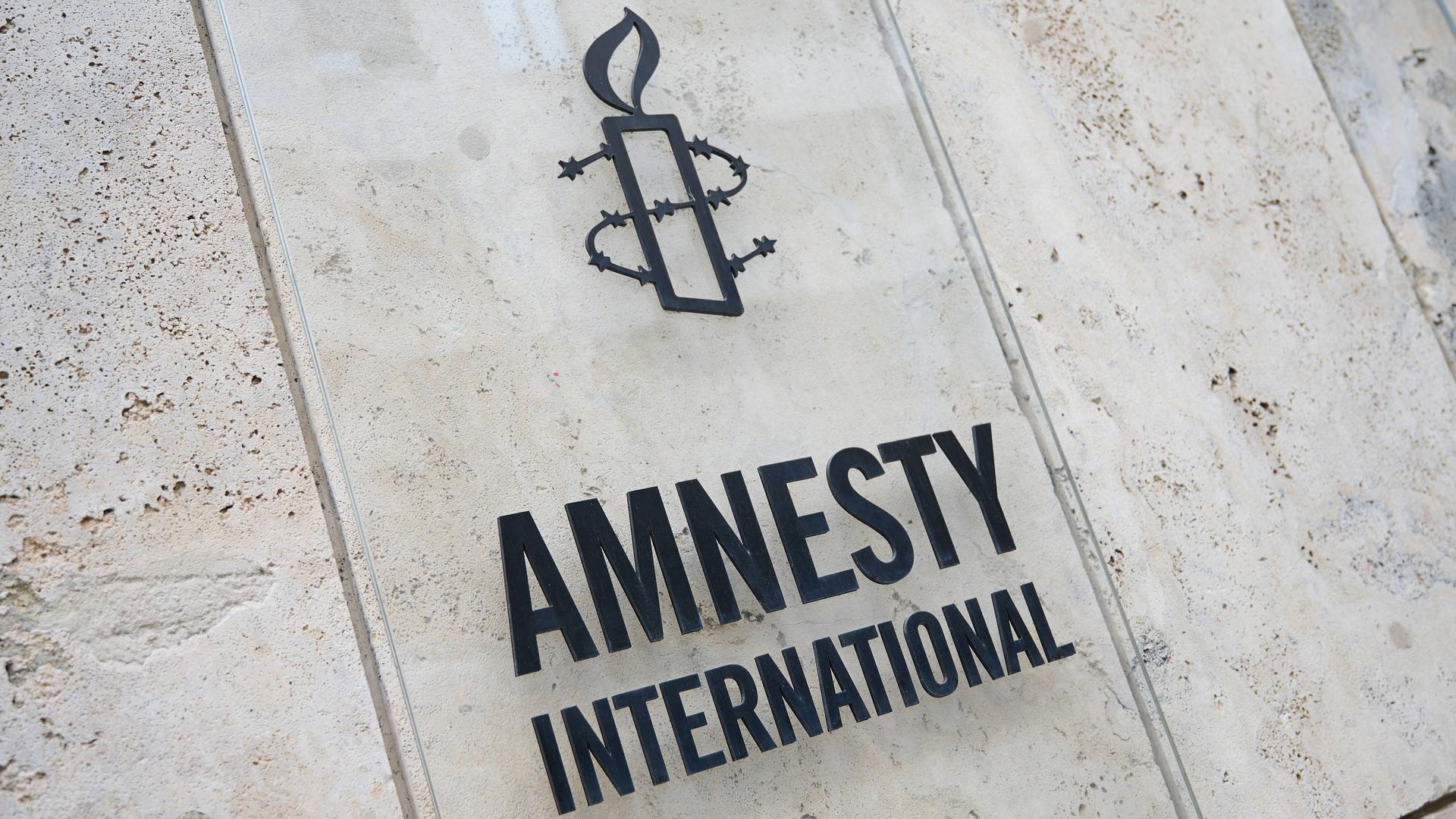 Der Schriftzug und das Logo von Amnesty International auf einer Steinwand.