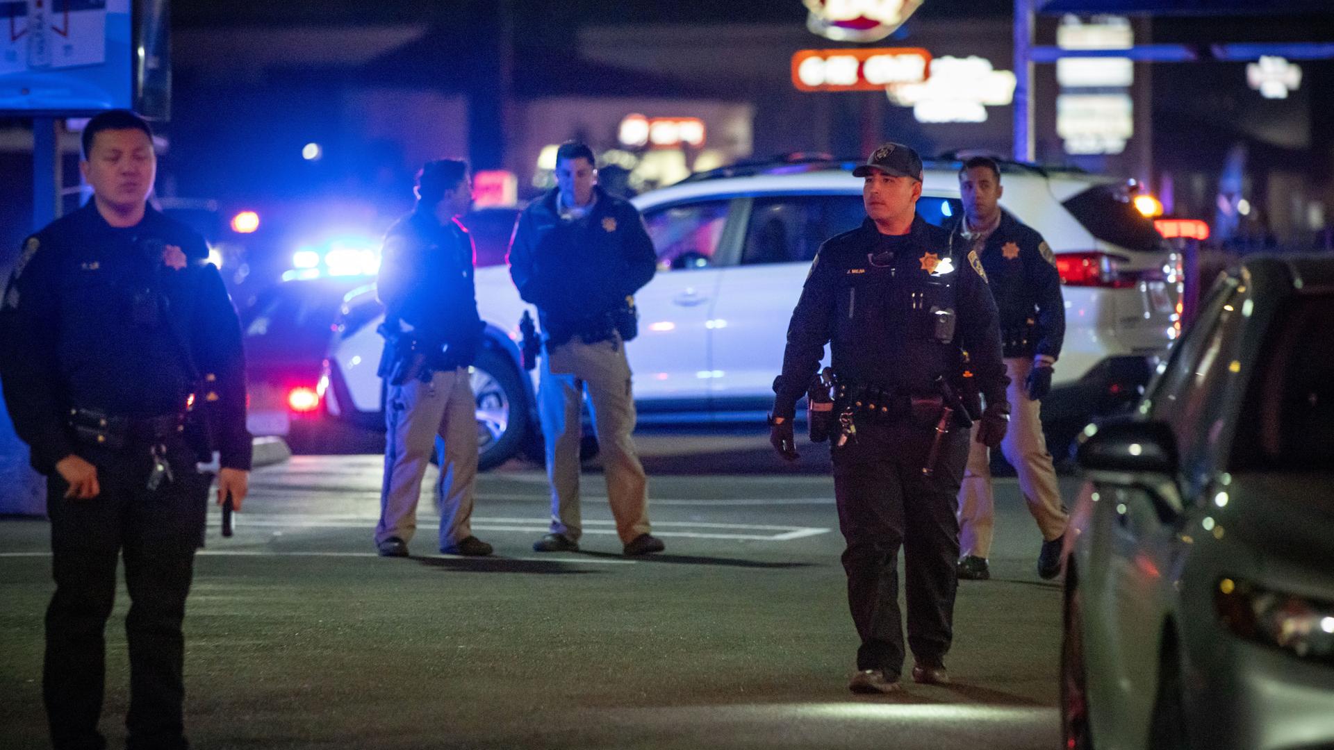 Einsatzkräfte gehen über einen Parkplatz in der Nähe eines Tatorts, nachdem Schüsse gefallen waren. 