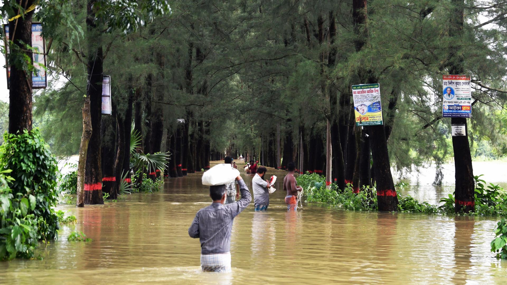 Menschen waten durch die Fluten in Feni, Chittagong, Bangladesh, am 23. August 2024, während einer Überschwemmung.