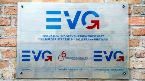Ein Schild zeigt das Logo der Gewerlkschaft EVG an einer rötlichen Klinkerwand.