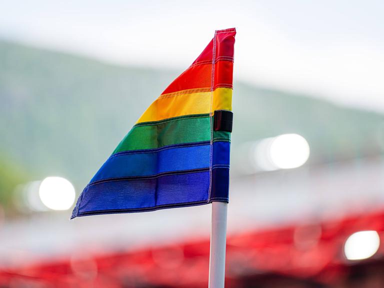 Eine Eckfahne in Regenbogenfarben in einem Fußballstadion.