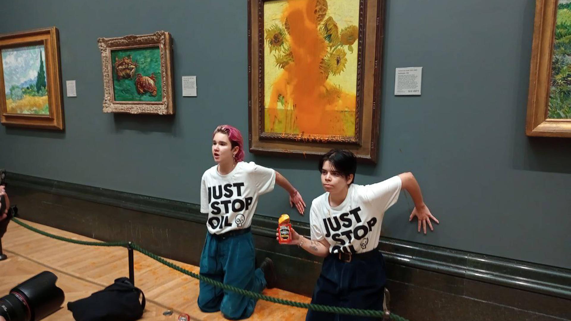 Klimaaktivistinnen knien vor den Sonnenblumen-Gemälde von van Gogh, dass von Tomatensuppe übergossen ist. 