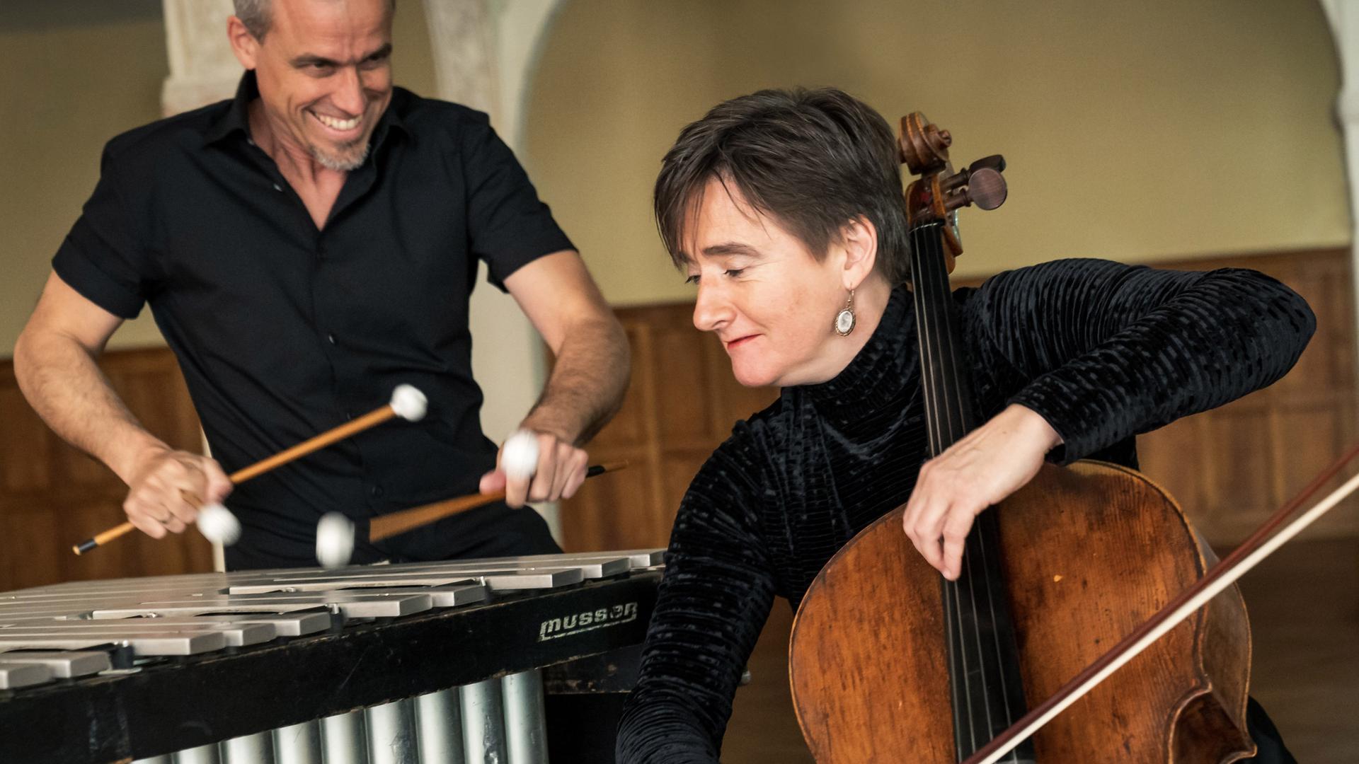 Oli Bott steht hinter seinem Vibraphon, während Anna Carewe davor sitzt und ihm zugewandt ihr Cello spielt. Oli Bott steht hinter seinem Vibraphon, während Anna Carewe davor sitzt und ihm zugewandt ihr Cello spielt.