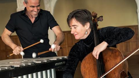 Oli Bott steht hinter seinem Vibraphon, während Anna Carewe davor sitzt und ihm zugewandt ihr Cello spielt.