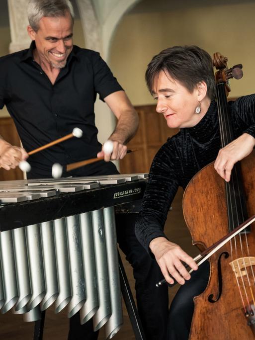 Oli Bott steht hinter seinem Vibraphon, während Anna Carewe davor sitzt und ihm zugewandt ihr Cello spielt.
