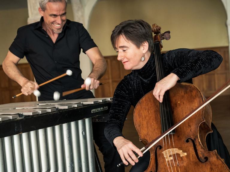 Oli Bott steht hinter seinem Vibraphon, während Anna Carewe davor sitzt und ihm zugewandt ihr Cello spielt.