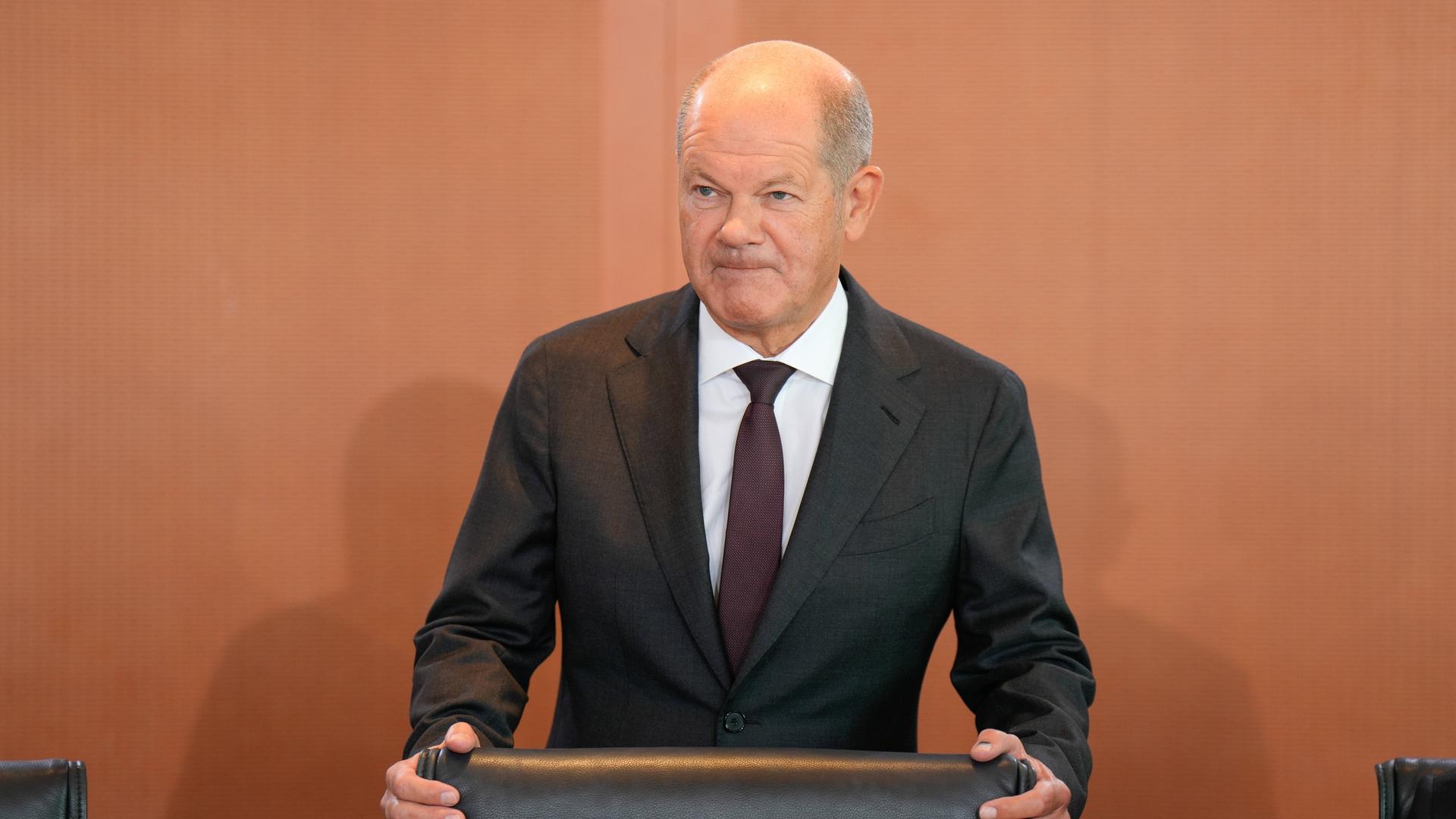 Bundeskanzler Olaf Scholz, den Stuhl festhaltend, vor der Kabinettssitzung 