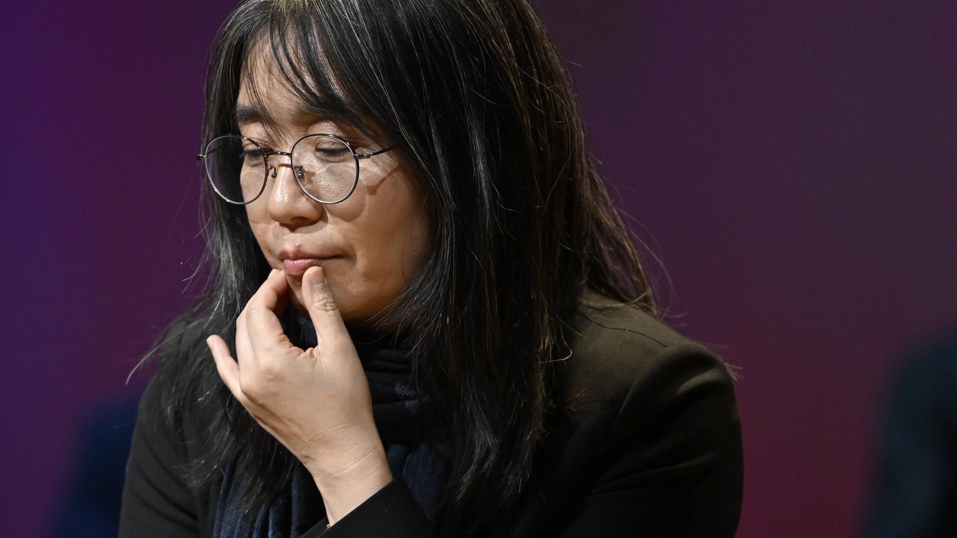 Autorin Han Kang, die sich in nachdenklicher Pose an die Lippe fasst Autorin Han Kang, die sich in nachdenklicher Pose an die Lippe fasst