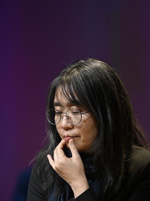 Autorin Han Kang, die sich in nachdenklicher Pose an die Lippe fasst Autorin Han Kang, die sich in nachdenklicher Pose an die Lippe fasst