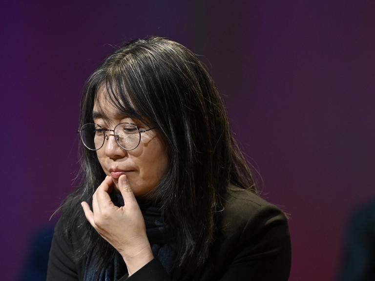 Autorin Han Kang, die sich in nachdenklicher Pose an die Lippe fasst Autorin Han Kang, die sich in nachdenklicher Pose an die Lippe fasst