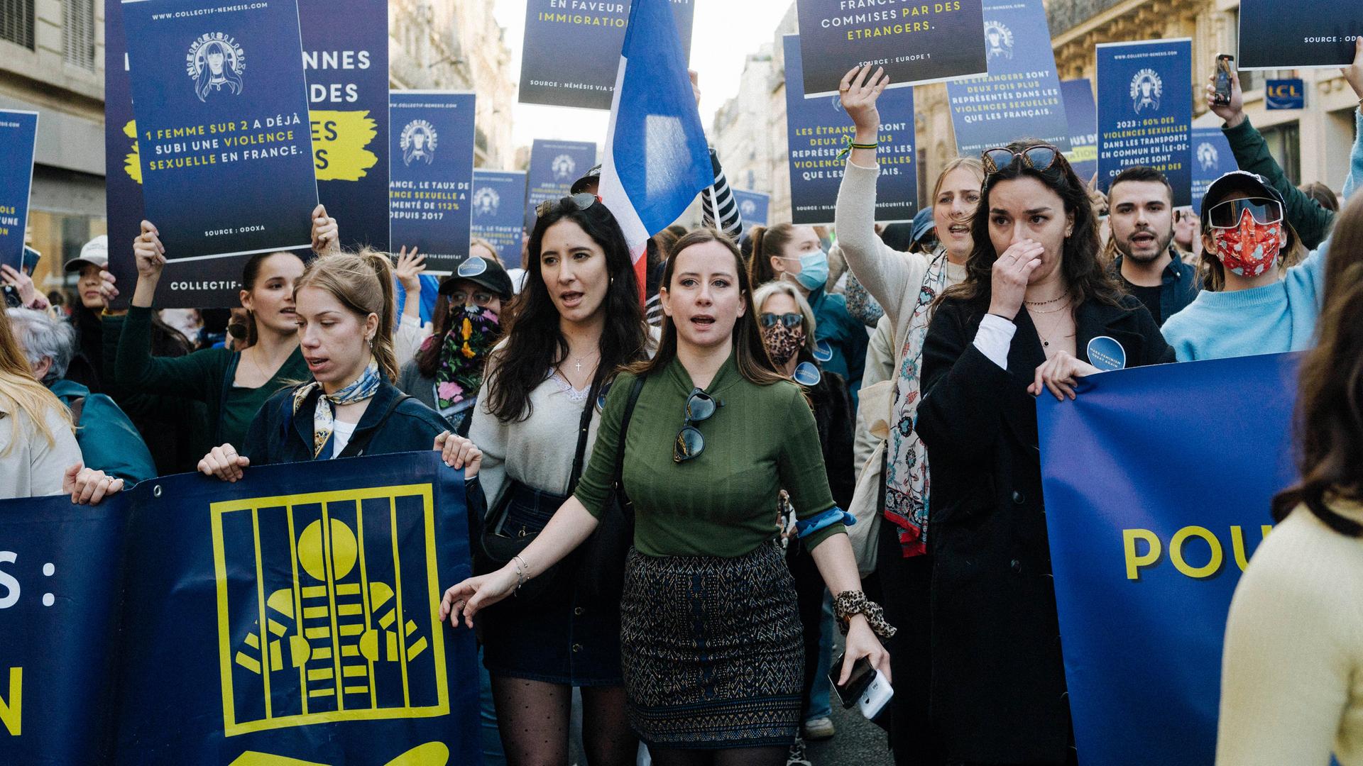 Eine Gruppe von demonstrierenden Frauen läuft durch die Straßen von Paris. Sie halten Schilder in die Luft. Eine Gruppe von demonstrierenden Frauen läuft durch die Straßen von Paris. Sie halten Schilder in die Luft.