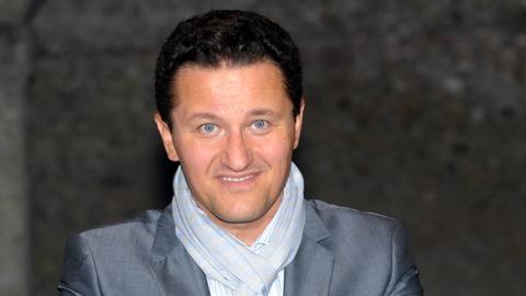 Piotr Beczała mit hellblauem Schal lächelt in die Kamera