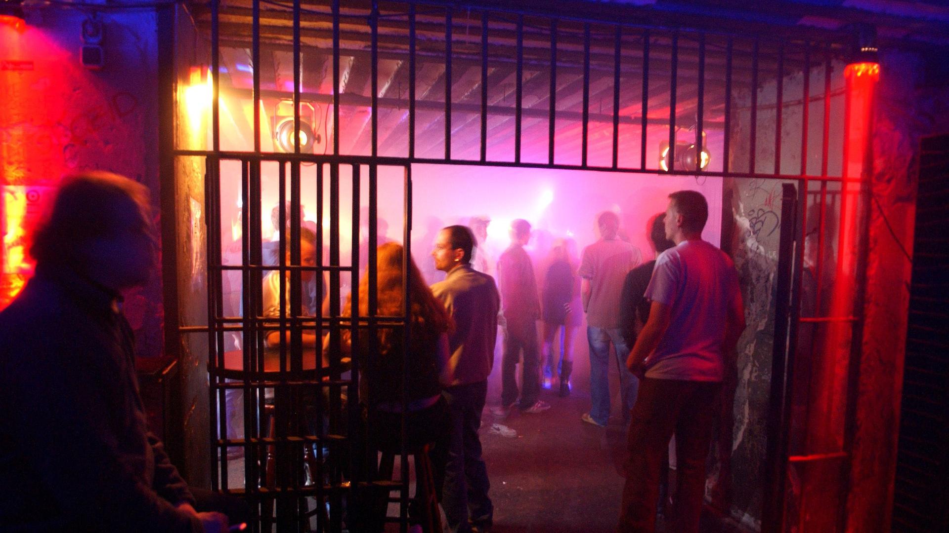Die Tür zu einem vergitterten Raum im Berliner Club Tresor ist geöffnet. Man sieht Menschen im bunten Licht tanzen. 