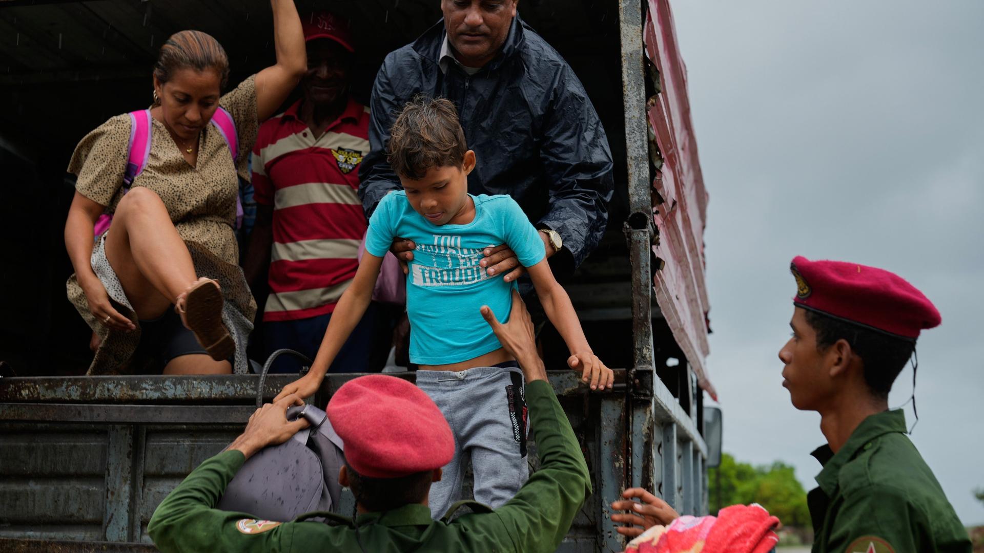 Sicherheitskräfte helfen in Canizo in Kuba Menschen in einen Lkw. Sicherheitskräfte helfen in Canizo in Kuba Menschen in einen Lkw.