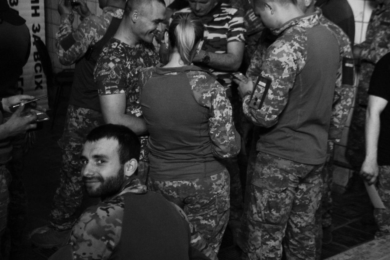 Ein junger Soldat schaut nach Wakartschuks zweitem Gig in die Kamera. Die anderen schauen sich Fotos an, die sie von Wakartschuk gemacht haben.