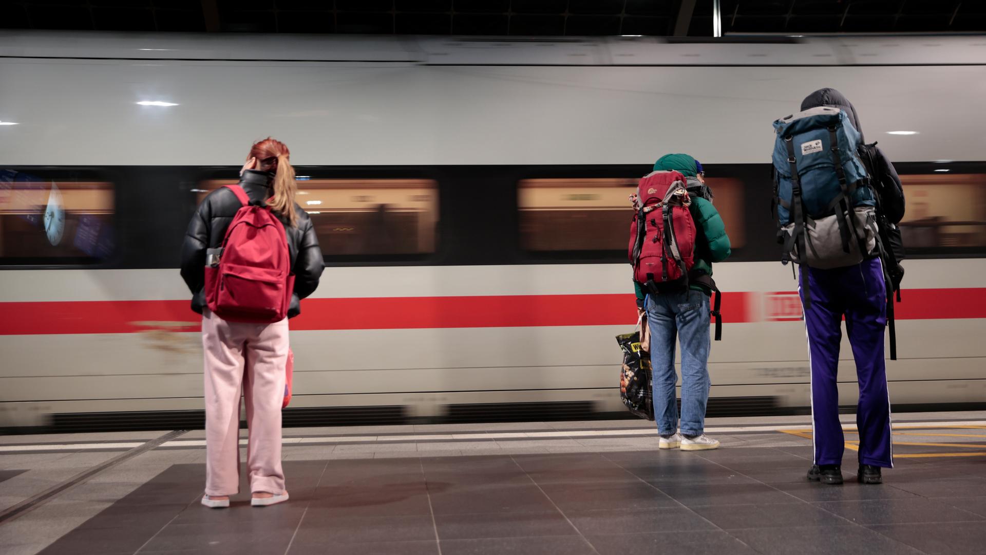 Reisende warten im Berliner Hauptbahnhof während der Einfahrt eines Zuges am Bahnsteig.