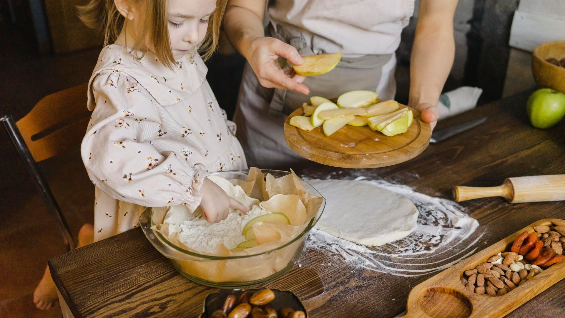 Tochter und Mutter backen gemeinsam einen Apfelkuchen.