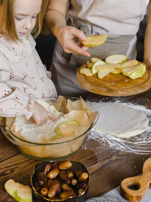 Tochter und Mutter backen gemeinsam einen Apfelkuchen.