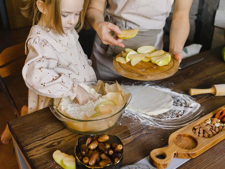 Tochter und Mutter backen gemeinsam einen Apfelkuchen.