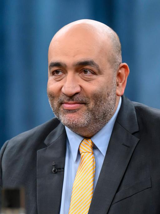 Porträt von Omid Nouripour (51 Jahre alter Mann mit kräftiger Statur, Glatze, gelber Krawatte und schwarzem Sacko), Vizepräsident des Deutschen Bundestages, Bündnis 90/Die Grünen als Gast beim Politiktalk Caren Miosga