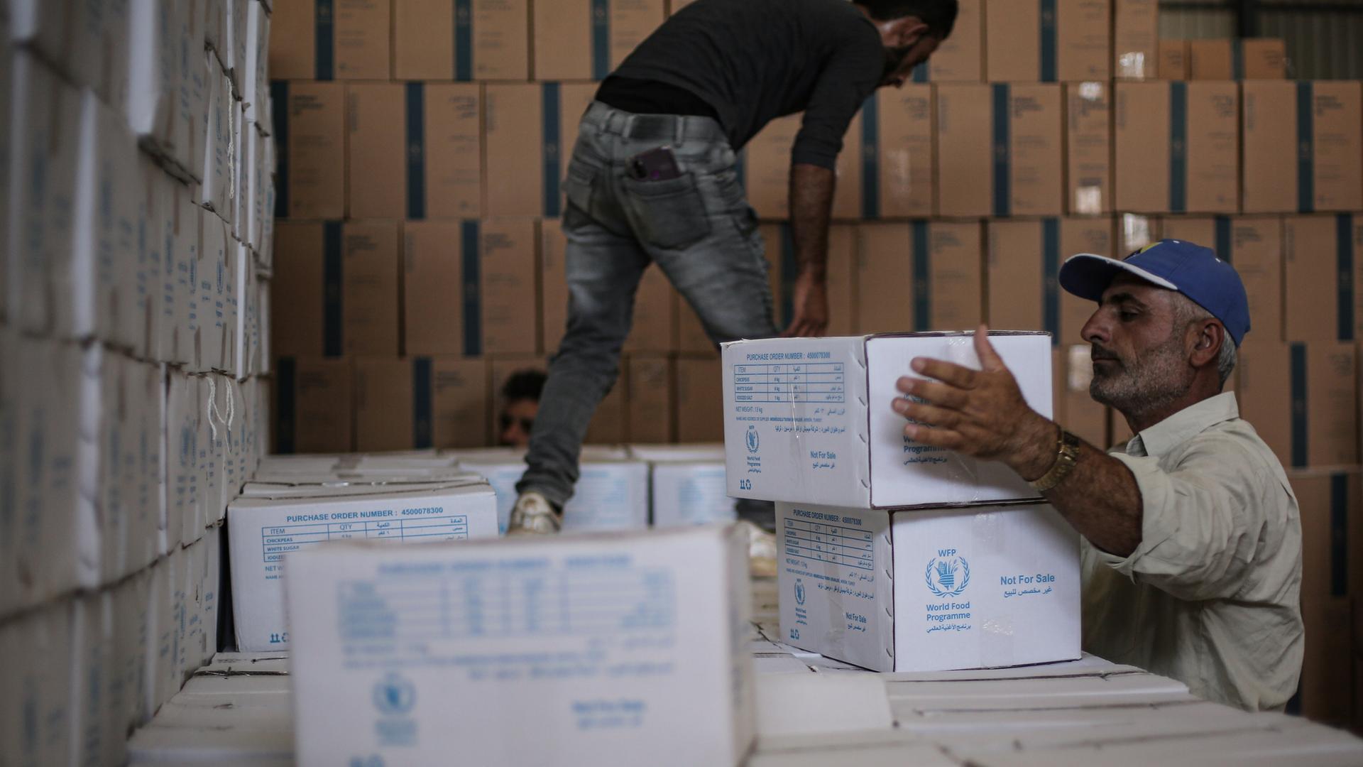 Männer laden Hilfsgüter des World Food Programme für Syrien an einem Grenzübergang zur Türkei in einen LKW. Männer laden Hilfsgüter des World Food Programme für Syrien an einem Grenzübergang zur Türkei in einen LKW.