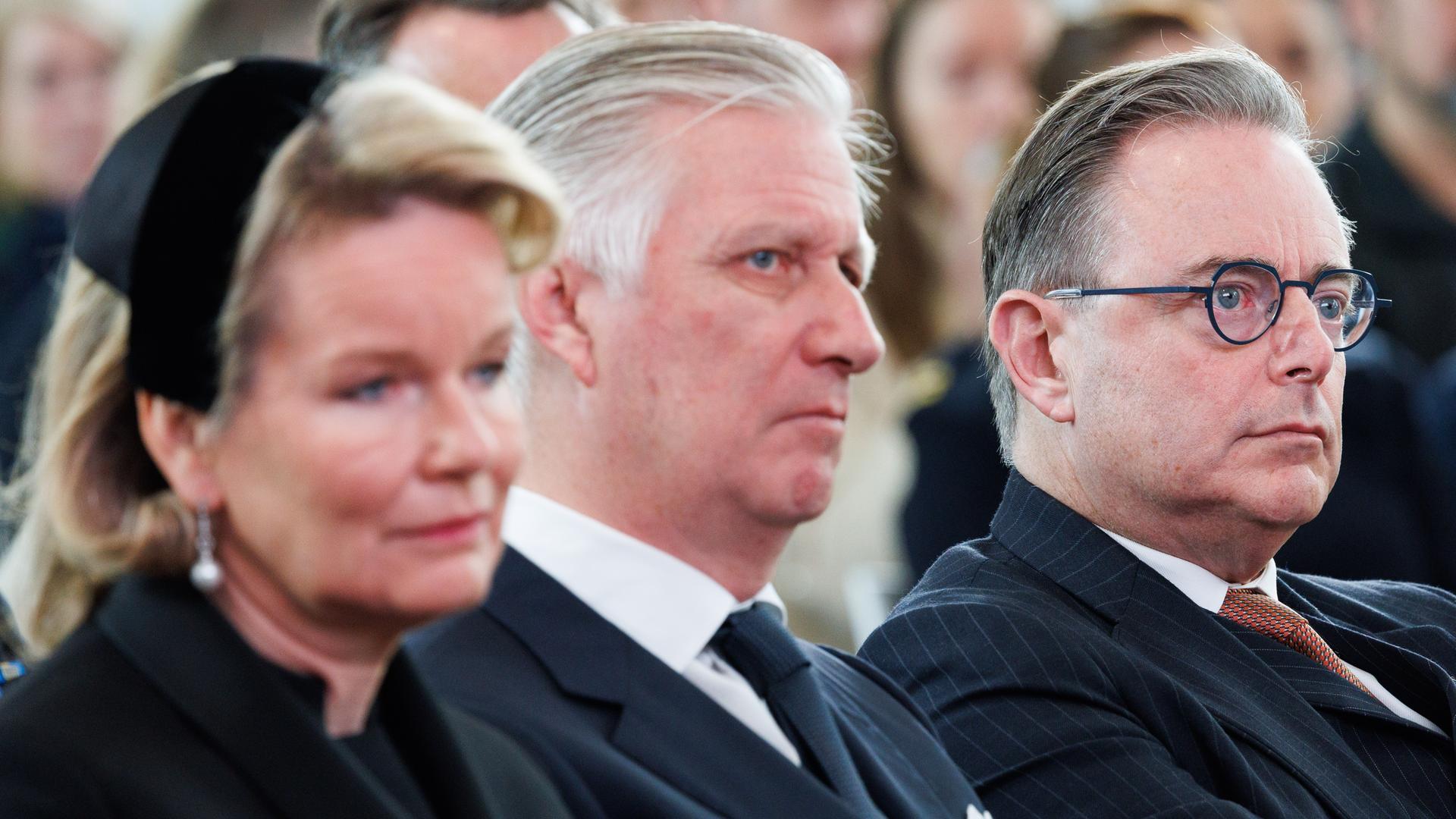 Das belgische Königspaar und Ministerpräsident De Wever sitzen nebeneinander. Nahaufnahme auf ihre Köpfe. 