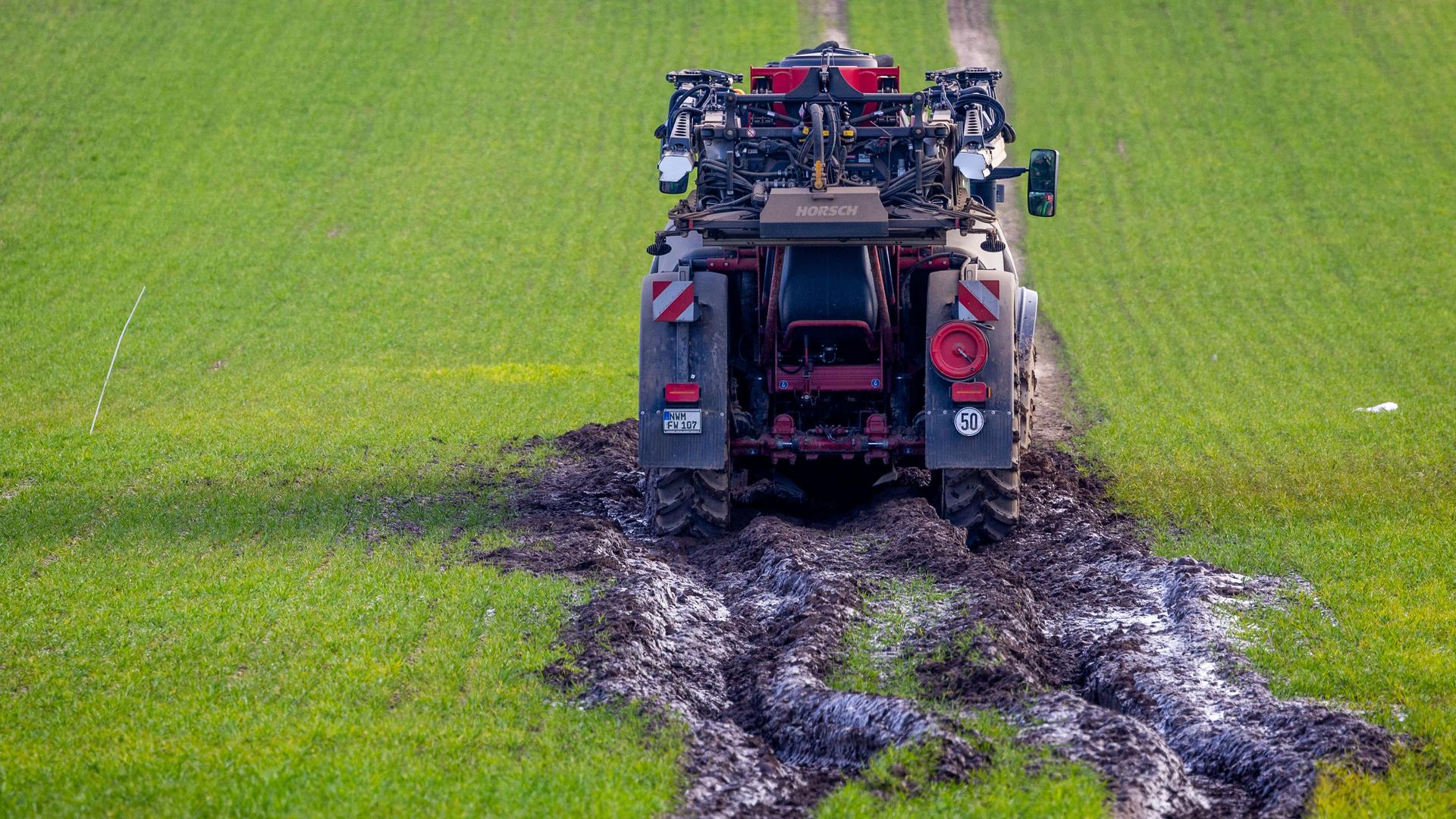 Ein Traktorgespann ist beim Ausbringen von Dünger im aufgeweichten Boden auf einem Feld steckengeblieben. 