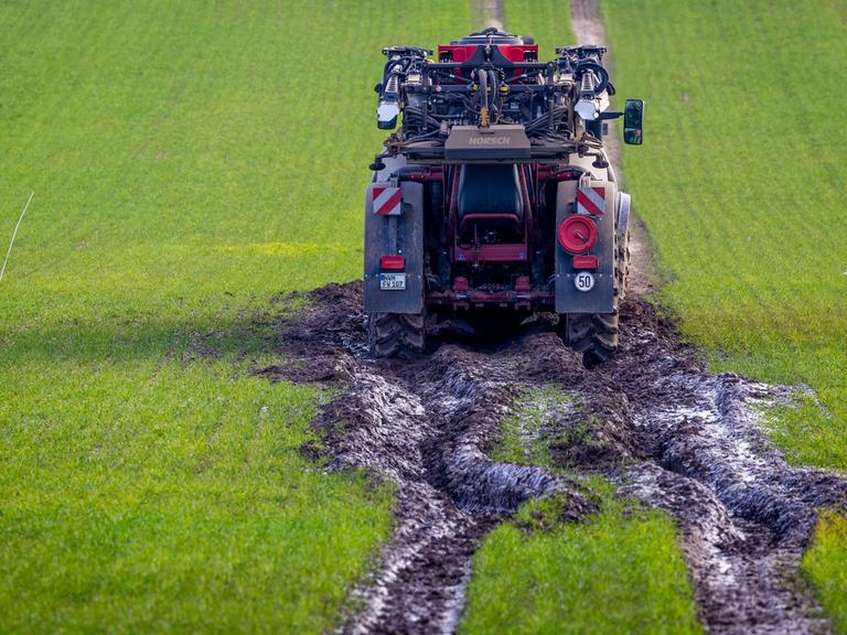Ein Traktorgespann ist beim Ausbringen von Dünger im aufgeweichten Boden auf einem Feld steckengeblieben. 